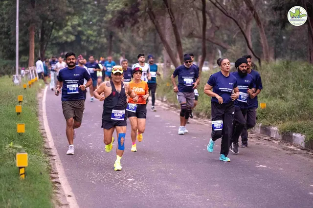 A group of runners in navy event T-shirts on the route, cones along the kerb