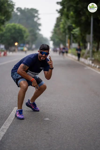 A runner crouching and pointing at the camera on the road