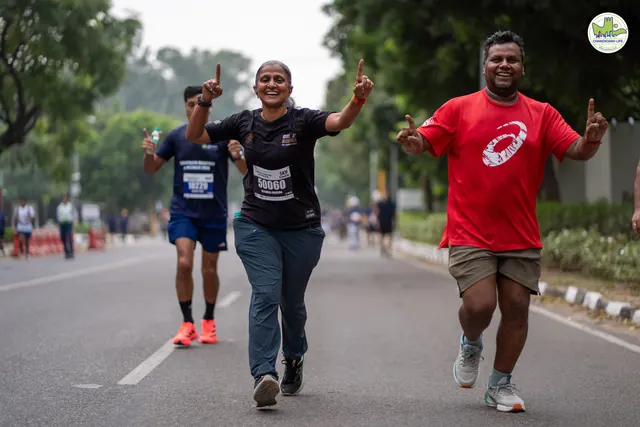 Three runners cheering with arms raised on the route