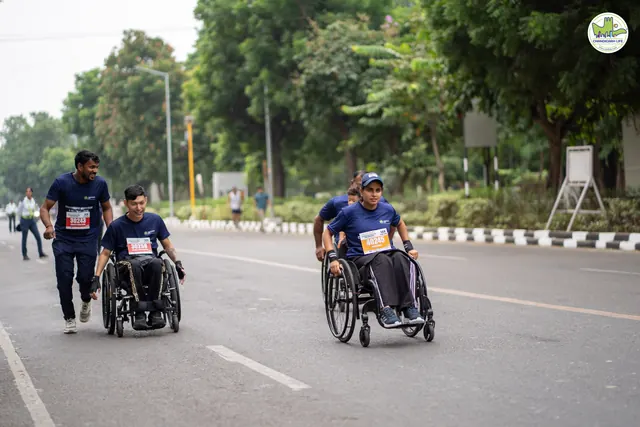 Two wheelchair racers on the road with a runner alongside