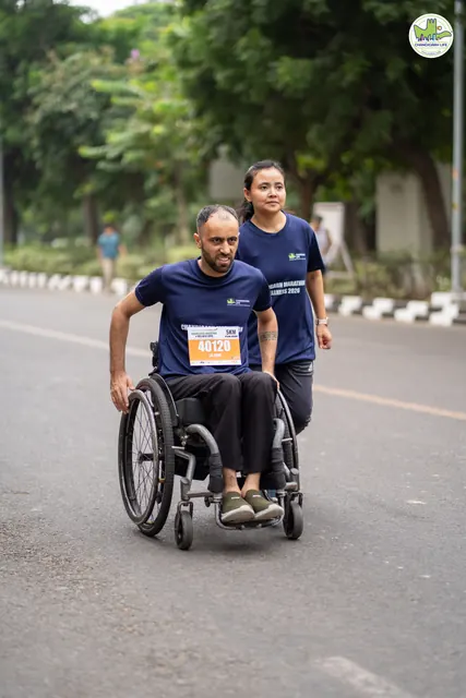 A wheelchair racer on the route with a runner behind him