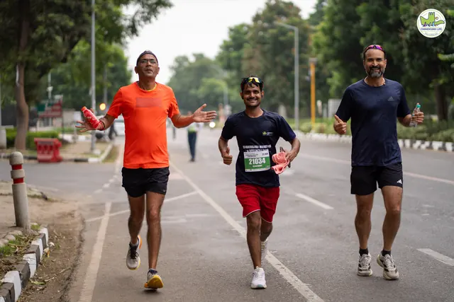 Three men running on the route, one in an orange T-shirt