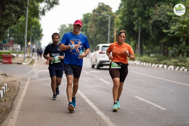 Runners in caps on the route with cars parked beyond