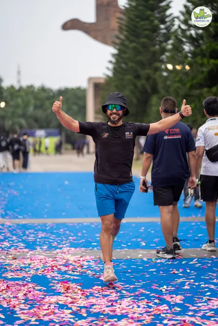 A finisher celebrating with thumbs up on the blue finish carpet covered in petals
