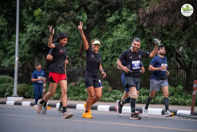 A group of runners waving as they pass on the route