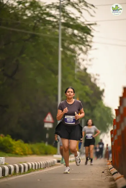 A runner on the road with the sun through the trees