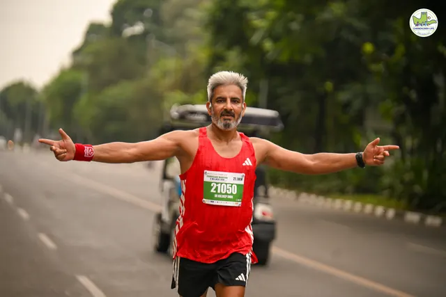 A runner in a red vest with arms spread wide on the route