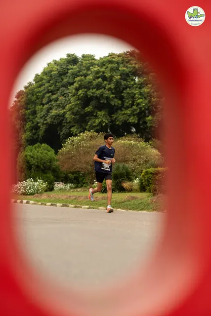A runner seen through the cut-out of a red traffic police barrier