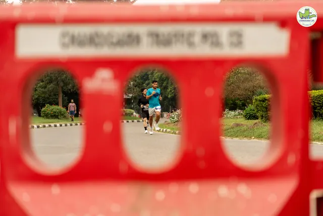 Runners seen through a red Chandigarh Traffic Police barrier