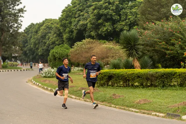Two runners on the road beside a trimmed hedge