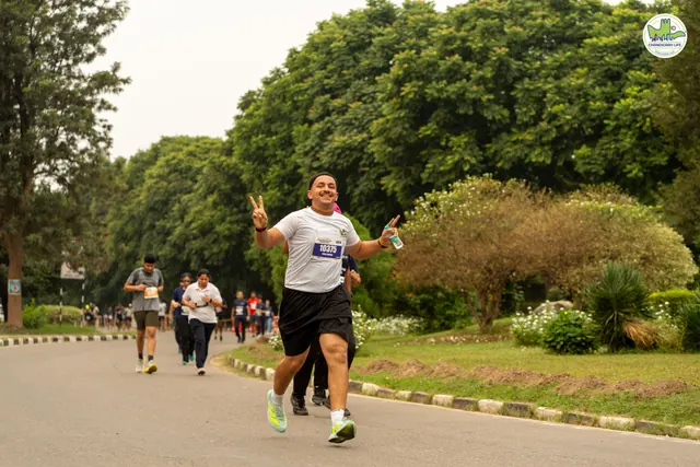A runner in white flashing a peace sign on the route