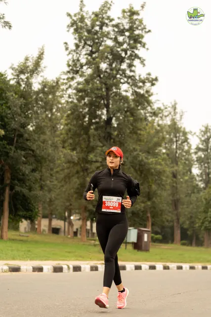 A woman in black and a red cap running on the road