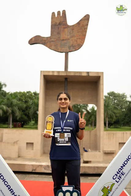 A woman holding a trophy in front of the Open Hand Monument