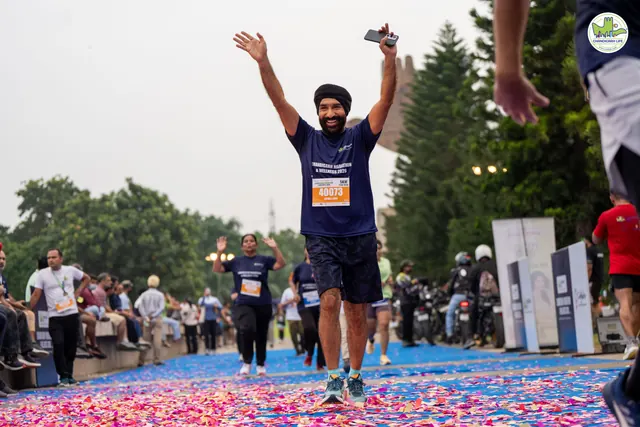 A man with both arms raised as he crosses the finish