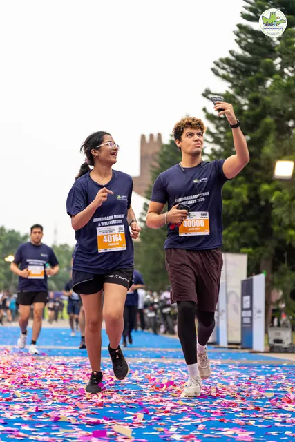 Two runners finishing together on the blue carpet