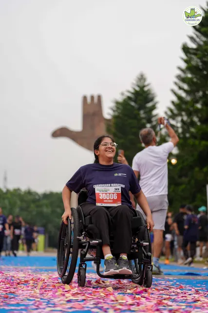 A smiling wheelchair user finishing on the blue carpet