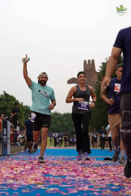 A man pointing skywards as he finishes beside a woman