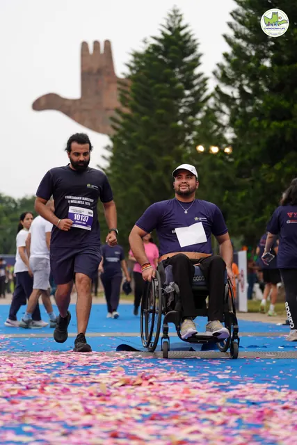A man walking beside a wheelchair user at the finish