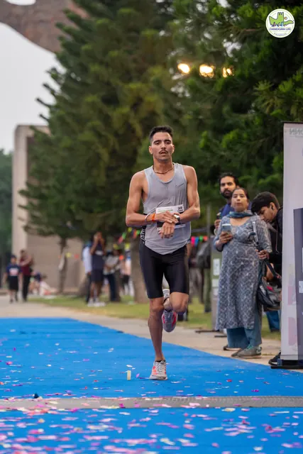 A runner in a white cap finishing on the blue carpet
