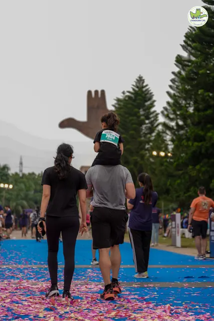A child on a parent's shoulders walking to the finish, seen from behind