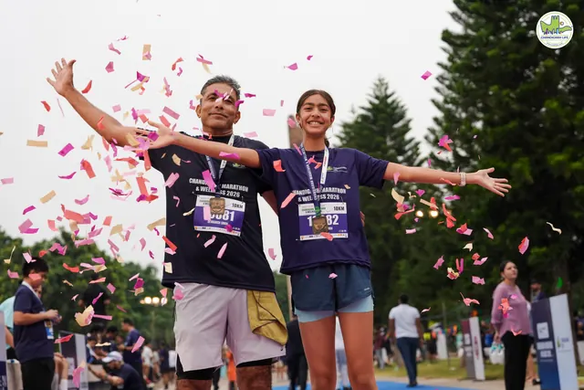 A couple with arms spread as petals fall at the finish