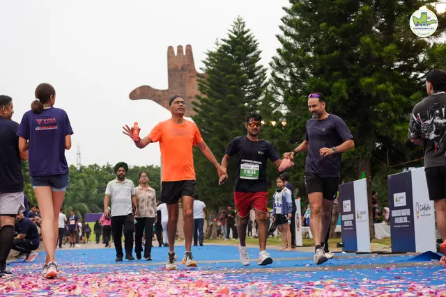 A group of runners finishing with the Open Hand Monument behind
