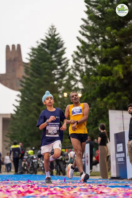 A man in yellow and a boy approaching the finish