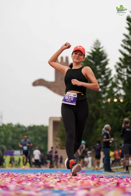 A woman in a red cap with an arm raised at the finish