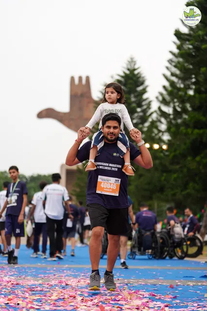 A man with a child on his shoulders at the finish