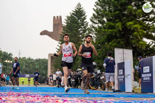 Two men finishing with the Open Hand Monument behind