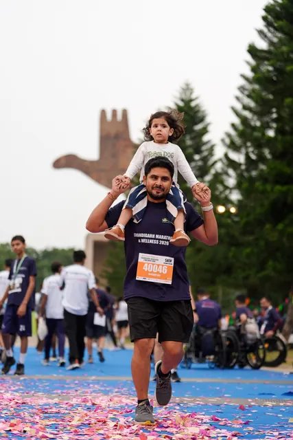 A man with a child on his shoulders crossing the finish