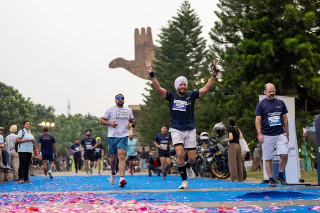 A man with arms up finishing with other runners